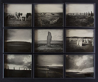 A 3x3 grid of glass photographs on black velvet in matte black frames. Depict Orkney landscapes of grassy hills, monoliths, cows, graves & shore